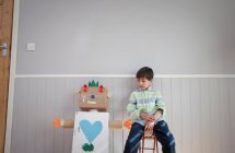 Junge sitzt neben selbstgebasteltem Spielzeugroboter — Stockfoto