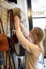 Woman hanging up bags in vintage clothes shop — Stock Photo