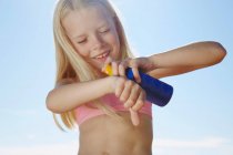 Menina pulverizando protetor solar na mão — Fotografia de Stock