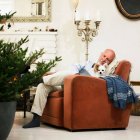 Hombre mayor durmiendo junto al árbol de Navidad - foto de stock