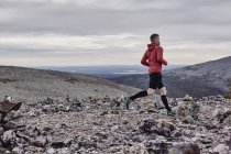 Man trail running on rocky cliff top, Kesankitunturi, Lapland, Finlândia — Fotografia de Stock