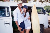 Portrait of couple by campervan with surfboard — Stock Photo
