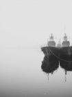 Ships docked in still harbor in mist — Stock Photo