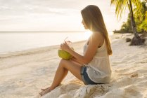 Junge Frau trinkt Kokosmilch am Strand von Bohol, Philippinen — Stockfoto