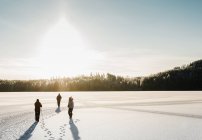 Tre persone neve coperto attraverso il campo innevato — Foto stock