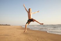Хлопчик стрибає на пляжі, портрет — стокове фото