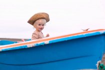 Тоддлер девушка сидит в лодке на пляже — стоковое фото