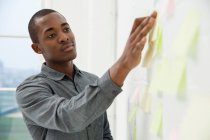 Young man sticking adhesive notes to wall — Stock Photo