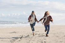 Des femmes souriantes courent sur la plage — Photo de stock