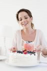 Mulher madura servindo frutas bolo coberto olhando para baixo sorrindo — Fotografia de Stock