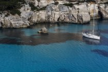 Scogliere di Cala Macarella e barca a vela, Minorca, Spagna — Foto stock