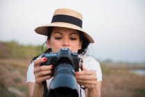 Mujer usando sombrero tomando fotografía - foto de stock