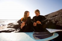 Couple assis sur la plage avec planche de surf — Photo de stock