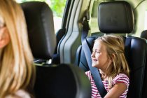 Fille souriant sur le siège arrière de la voiture — Photo de stock