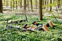 Mountain bikers relaxing in forest — Stock Photo
