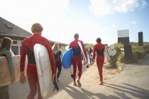 Группа серферов, направляющихся к пляжу, несущих доски для серфинга — стоковое фото