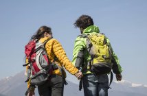 Rear view of hiking couple in front of snow capped mountain, Vogogna, Verbania, Piemonte, Italy — Stock Photo