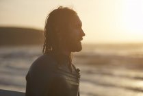 Joven surfista masculino mirando desde la playa, Devon, Inglaterra, Reino Unido - foto de stock