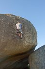 Vista trasera del joven escalando con cuerdas en la roca - foto de stock