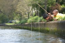 Хлопці рибалять на березі річки разом — стокове фото