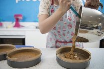 Frauenhände gießen in Bäckerei Masse in Kuchenform — Stockfoto