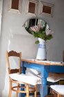 Blumenvase auf dem Tisch, Spiegel an der Wand im Zimmer — Stockfoto