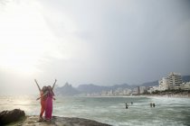 Portrait of two young women with arms raised on Ipanema beach, Rio De Janeiro, Brazil — Stock Photo