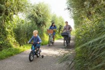 Family cycling down on country lane — Stock Photo