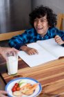 Menino fazendo lição de casa enquanto mãe servindo lanches e leite — Fotografia de Stock
