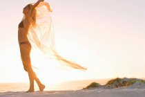 Frau spielt mit Sarong am Strand — Stockfoto