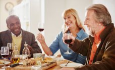 Senioren stoßen beim Abendessen an — Stockfoto