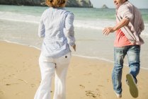 Супружеская пара, бегущая по пляжу, Камаре-сюр-мер, Британия, Франция — стоковое фото