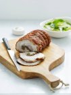 Roast pork loin with knife on cutting board — Stock Photo