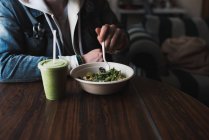 Junger Mann sitzt am Tisch, isst Salat, Mittelteil — Stockfoto