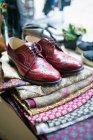 Vintage red brogue shoes on top of fabric pile — Stock Photo