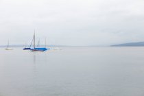 Sailboats on still ocean under cloudy sky — Stock Photo