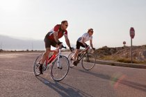 Велогонщики на сельской дороге по морю — стоковое фото