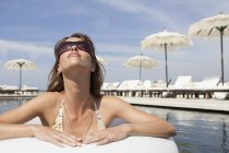 Cool молода жінка, що носить відтінків, притулившись біля басейну готелю beach resort, Майорка, Іспанія — стокове фото