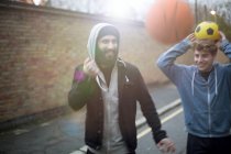 Two men walking in street, holding football — Stock Photo