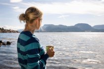 Woman with coffee by sea and mountains — Stock Photo