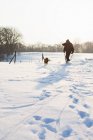 Uomo cane da passeggio nel campo innevato — Foto stock