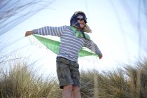 Jeune garçon sur la plage, vêtu d'une robe chic, faisant semblant de voler — Photo de stock