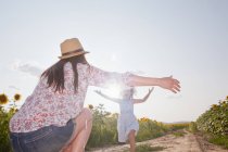 Girl running through field to mother with open arms — Stock Photo
