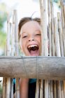 Boy smiling behind fence, focus on foreground — Stock Photo