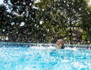 Menina salpicando na piscina — Fotografia de Stock