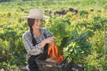 Молодая женщина с овощами, выращенными на ферме — стоковое фото