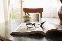Livre ouvert sur table avec lunettes — Photo de stock