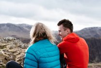Young couple sitting on hilltop, rear view, Keswick, Lake District, Cumbria, United Kingdom — Stock Photo