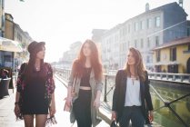 Trois jeunes femmes élégantes se promènent sur le front de mer du canal — Photo de stock