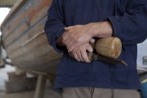 Cierre de manos de carpinteros que sostienen cincel en taller de barco - foto de stock